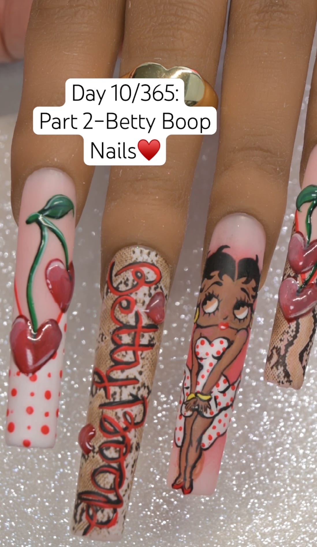 Full Betty Boop nail art set on long press-on tips — polka dots with 3D cherries, snakeskin with hand-lettered Betty Boop script, full-body Betty portrait nail, and 3D heart cherry accent