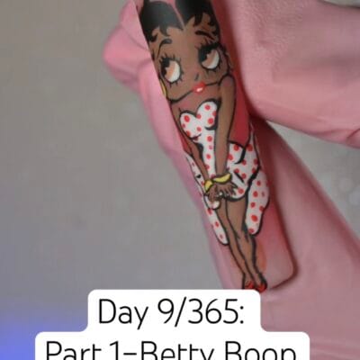 Hand-painted Betty Boop full-body character nail art on a single almond press-on tip — red lips, polka dot dress, freehand painted