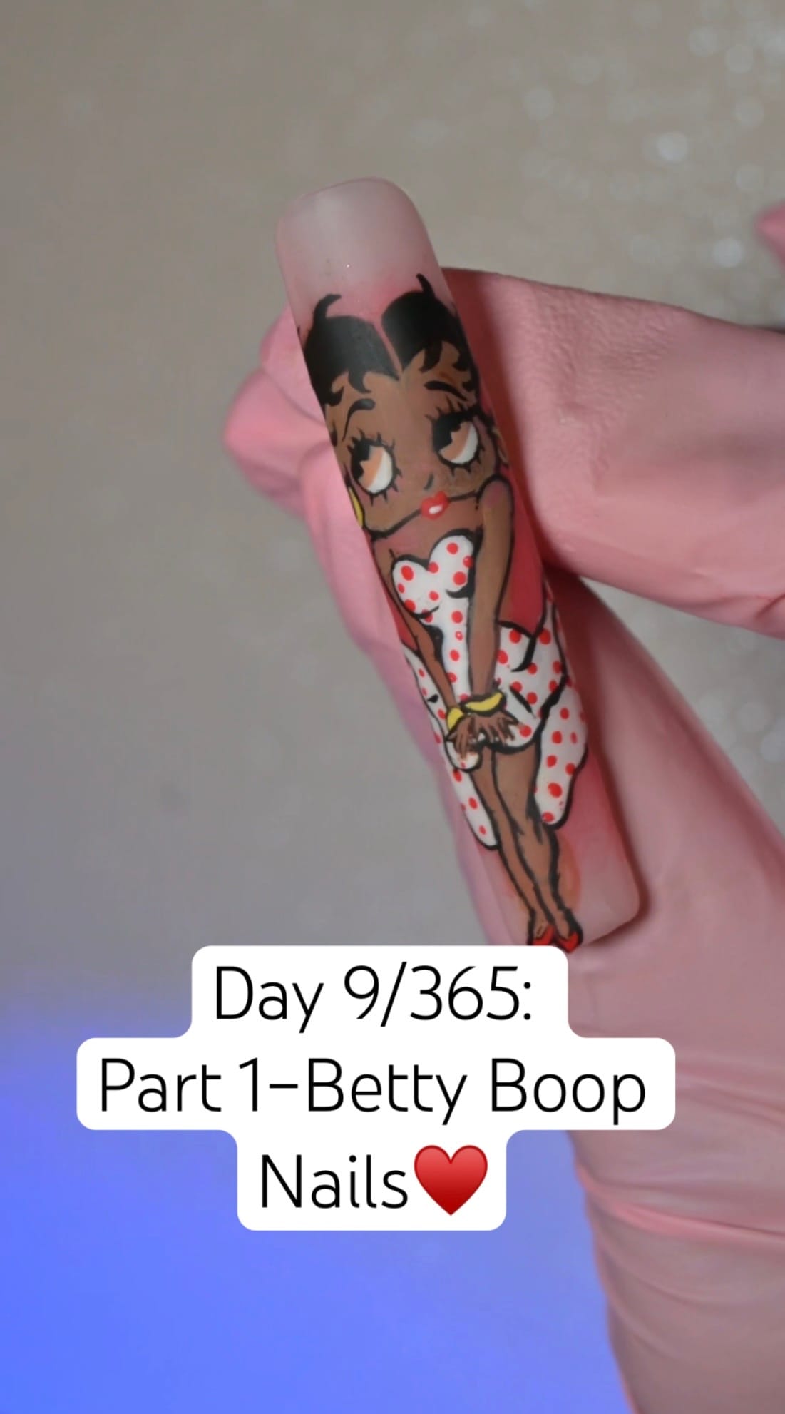 Hand-painted Betty Boop full-body character nail art on a single almond press-on tip — red lips, polka dot dress, freehand painted